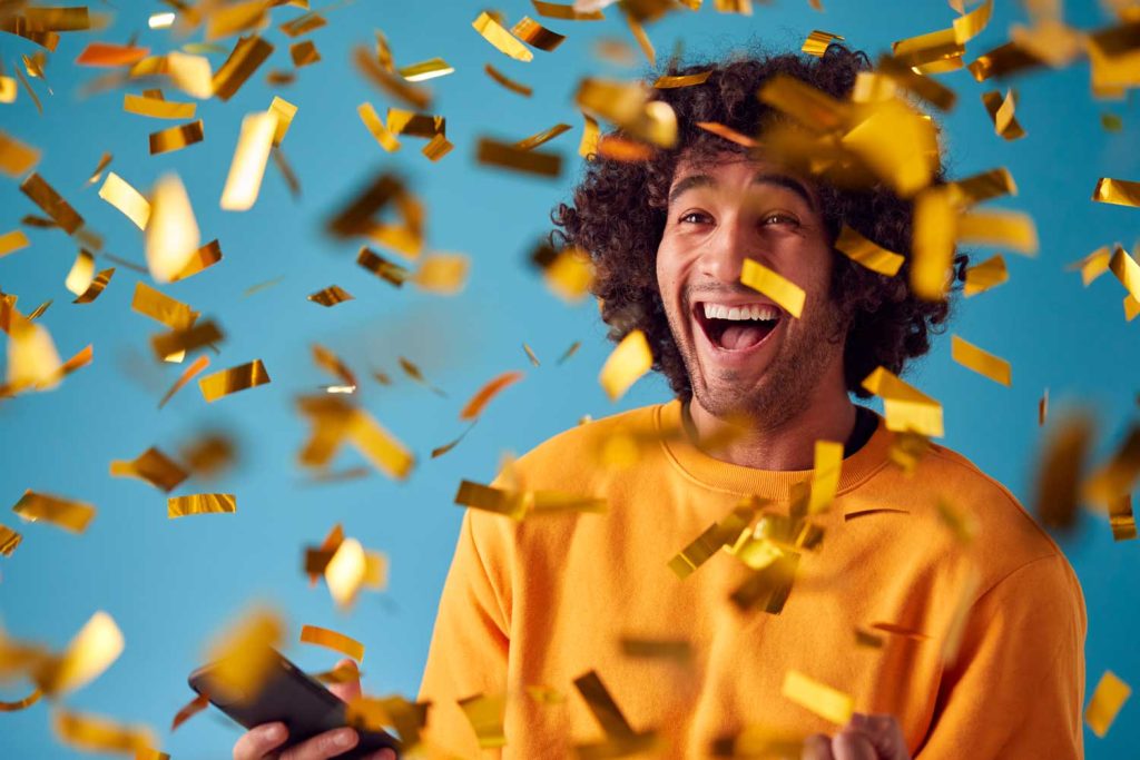 Man on a blue background with gold tickets, celebrating his prize draw win