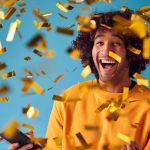 Man on a blue background with gold tickets, celebrating his prize draw win