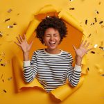 competition winner lady busting through a sheet of paper with gold tickets