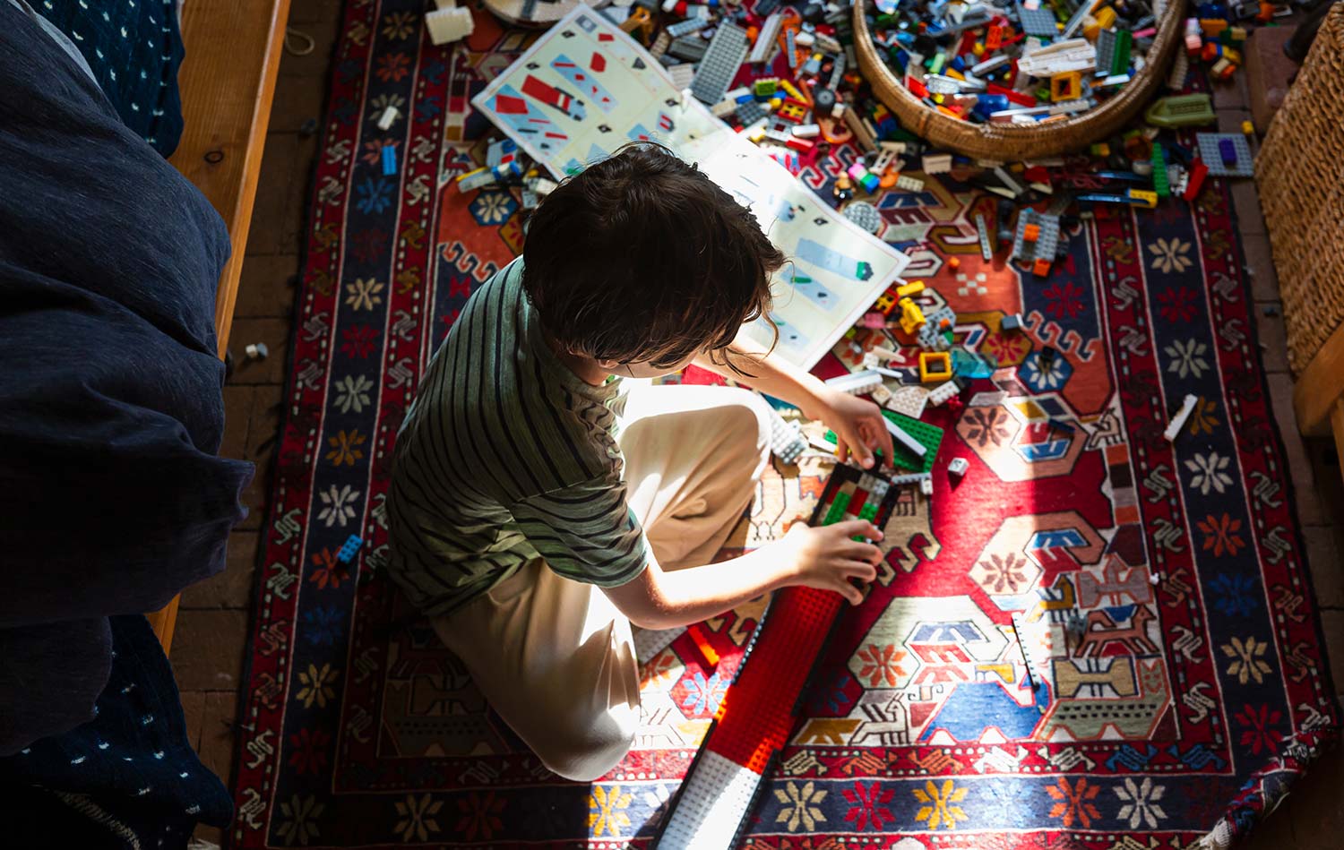 A boy, playing with Lego on his bedroom floor